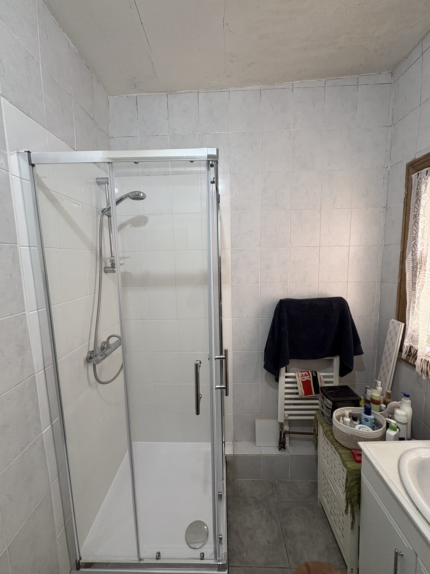 New glass shower screen and tray in a tiled bathroom, with the retained shower valve and rail on the wall