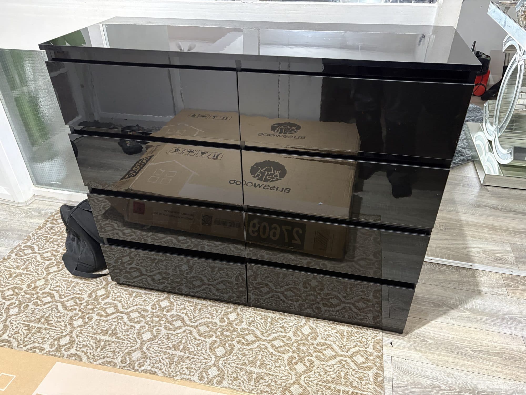 Assembled black gloss chest of drawers with eight drawers, standing in place