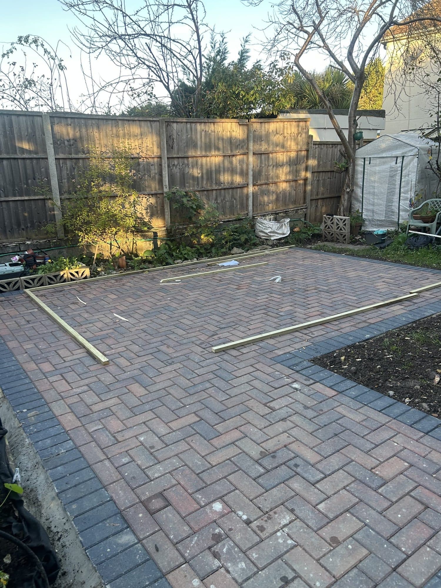 Paved garden area in Uxbridge with timber battens laid out on the paving, before the summer house was built