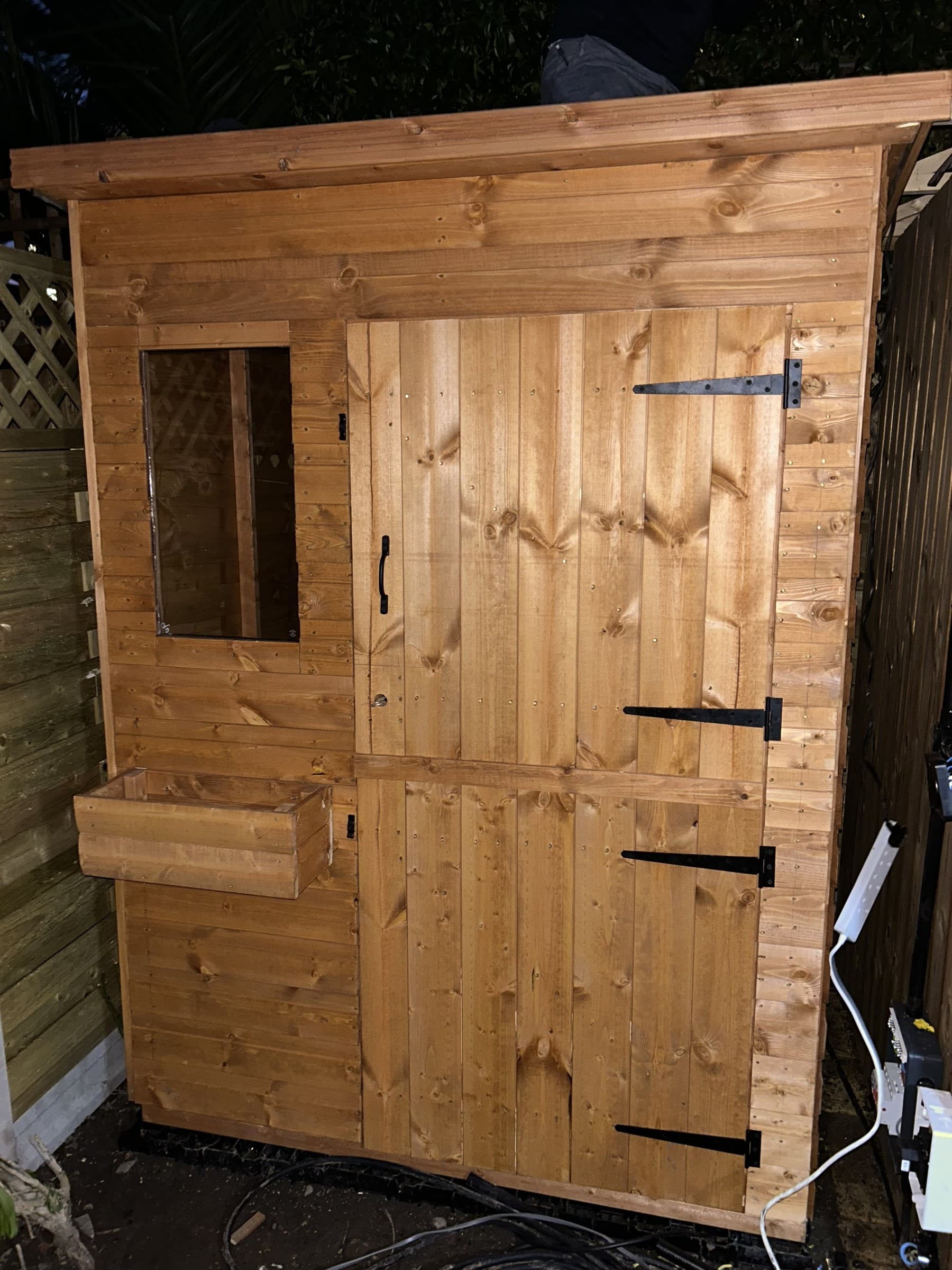 Assembled wooden garden shed panel with hinges and access hatch fitted
