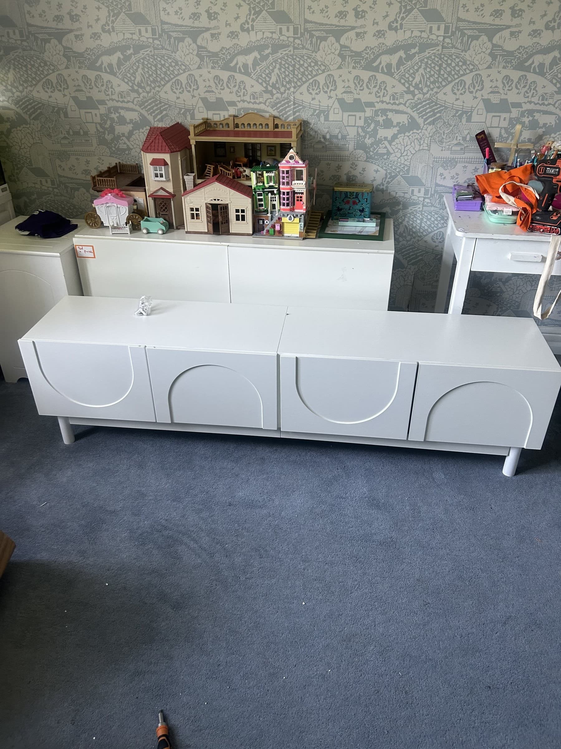 Assembled white gloss TV cabinet with round drawer pulls in a bedroom