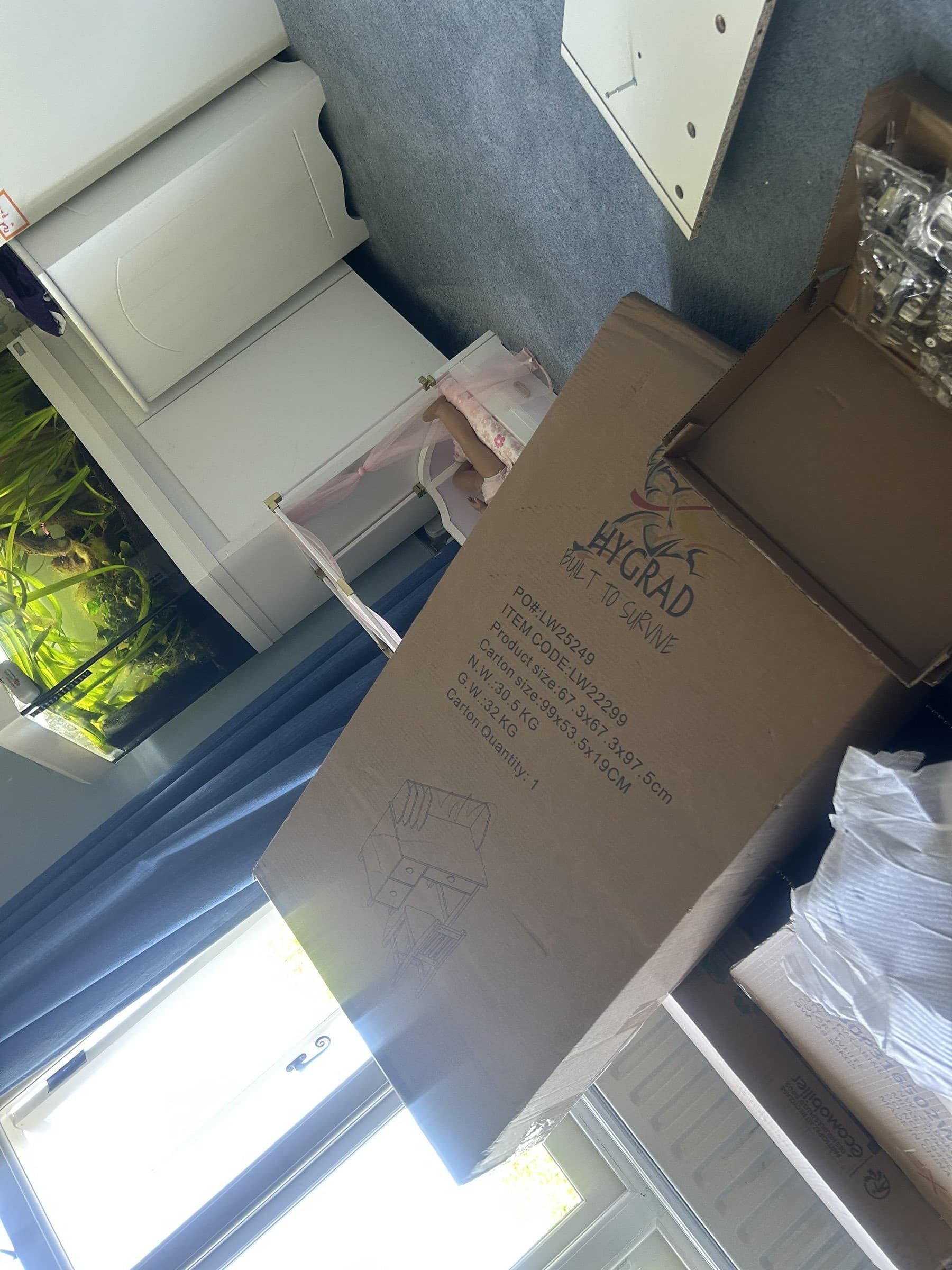 Flat-pack TV cabinet box ready for assembly in a child's bedroom
