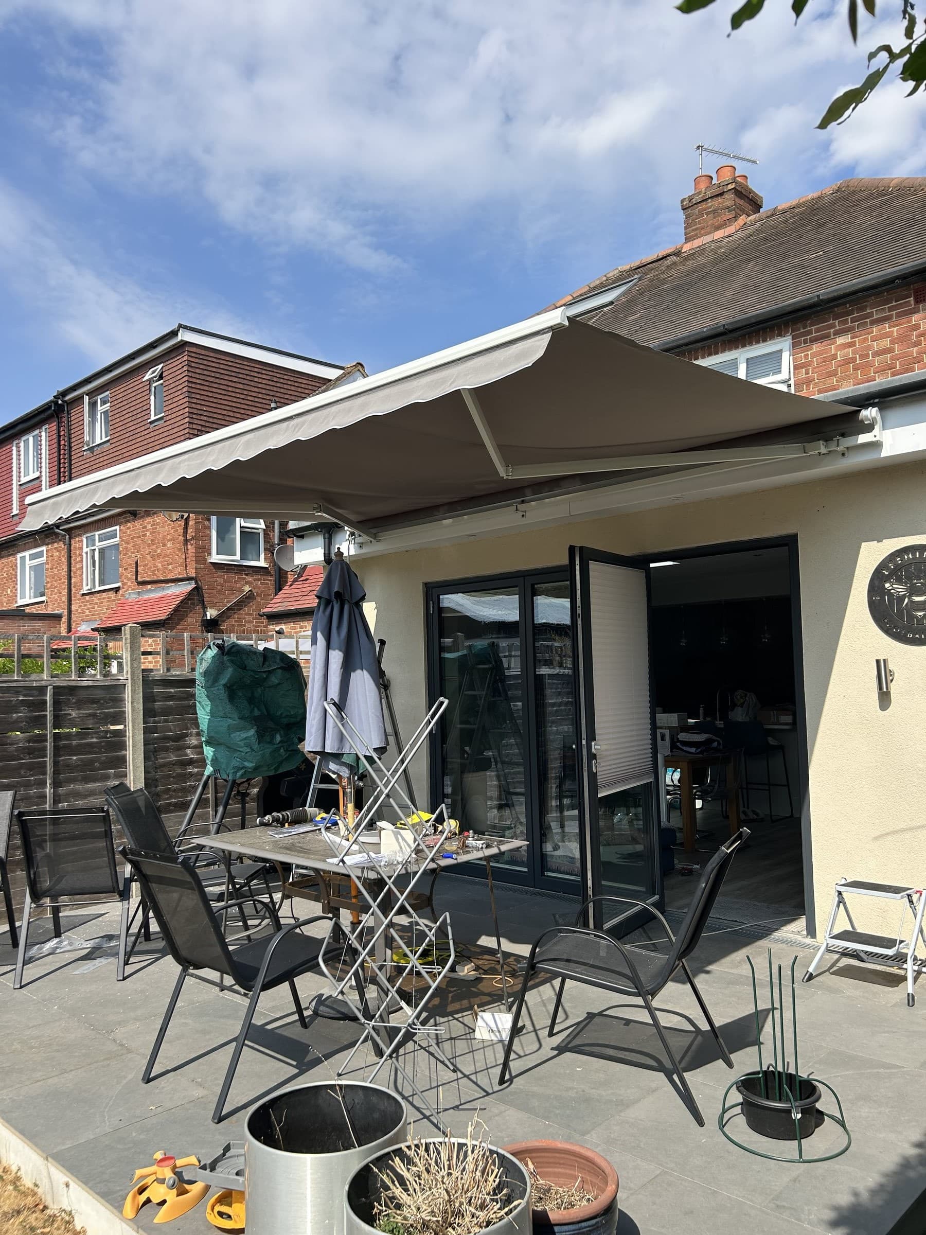 Large retractable awning extended above bifold doors on a house exterior