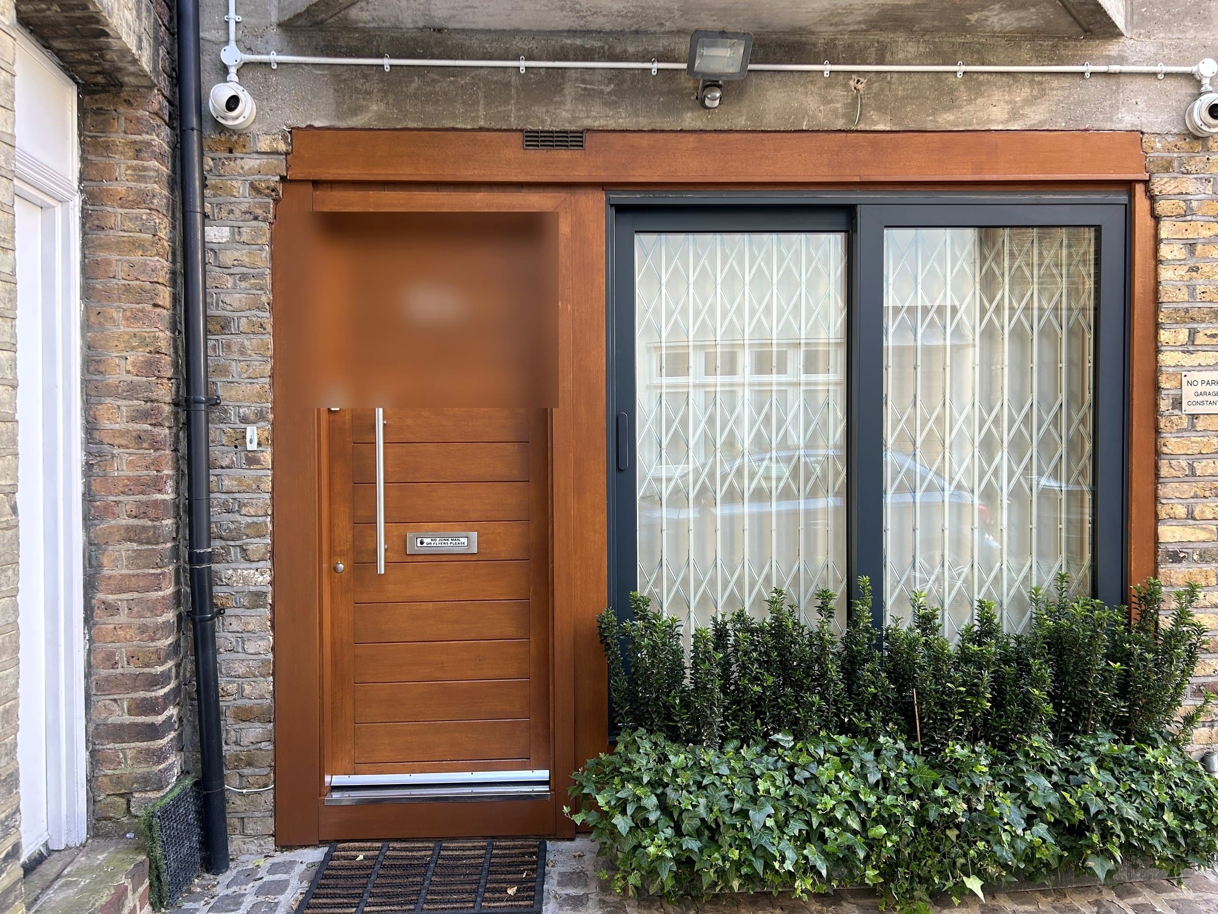 Wooden front door with a fresh, even varnish finish after refinishing, door number blurred for privacy