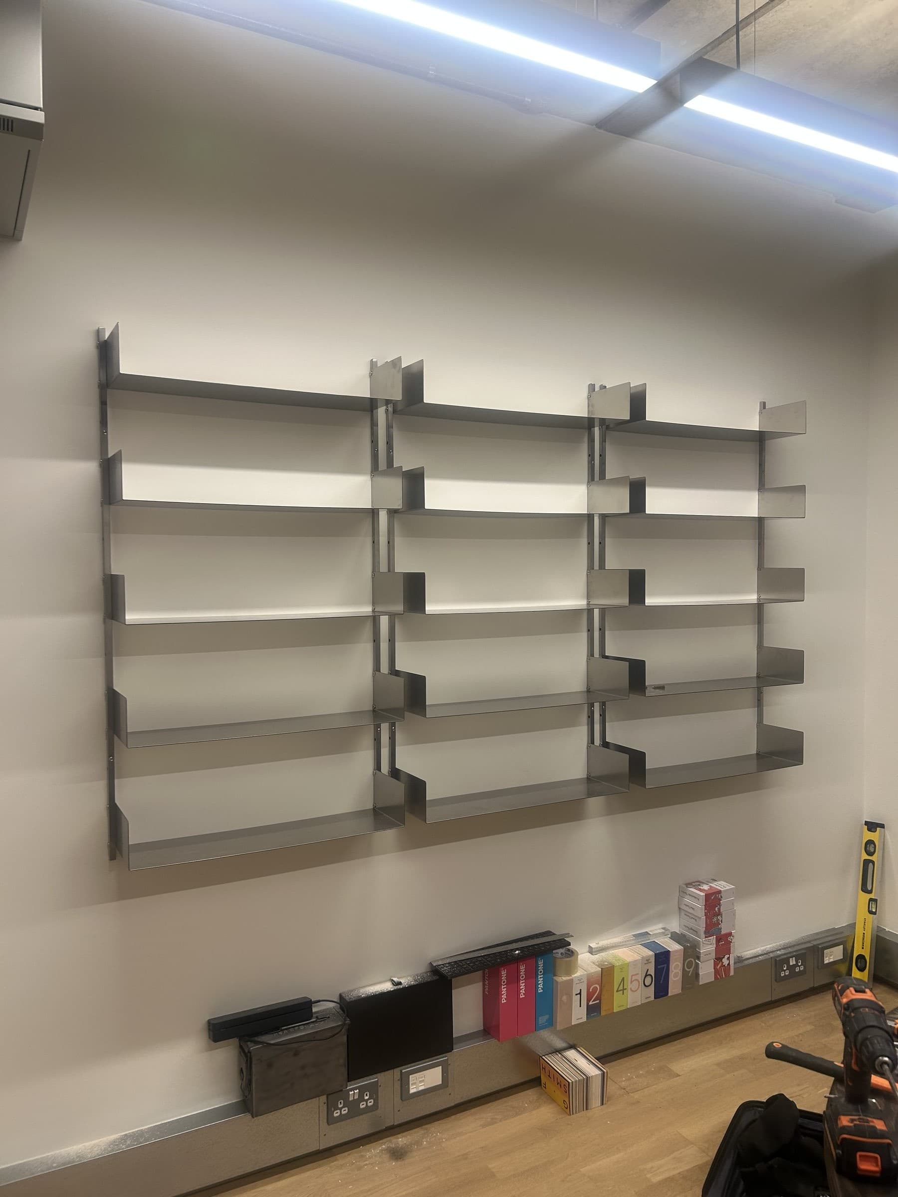 Stainless steel wall-mounted shelving unit installed in a commercial display space